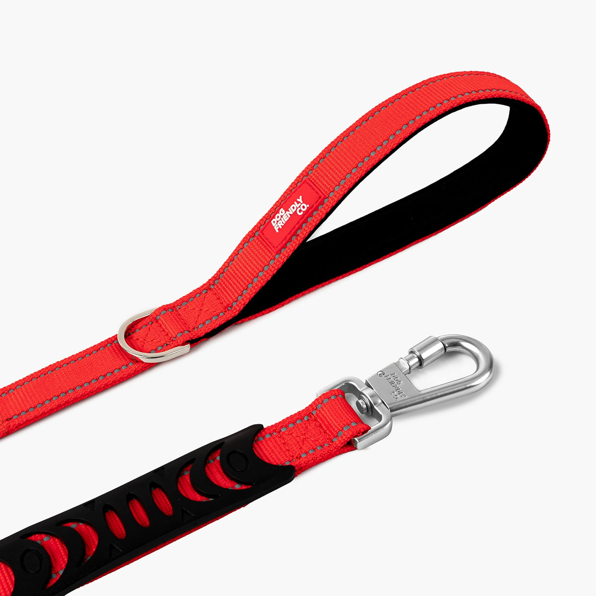 Close-up of the red bungee dog leash showing the padded handle, metal D-ring and heavy-duty clip.