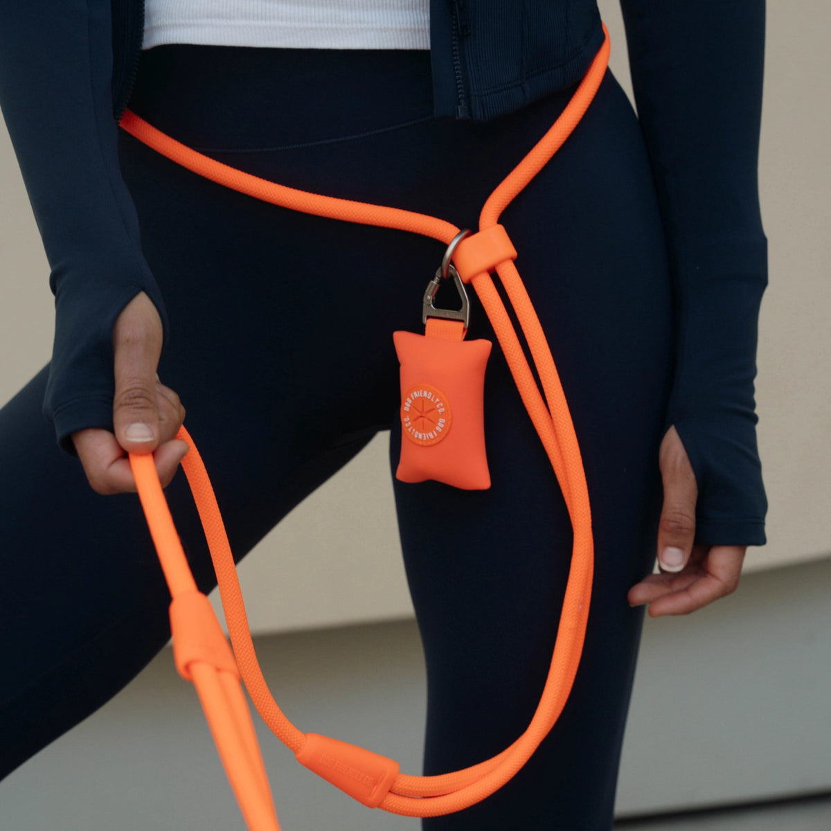 Close-up of the Orange hands-free leash worn around the waist with an orange poop bag holder attached to the leash.