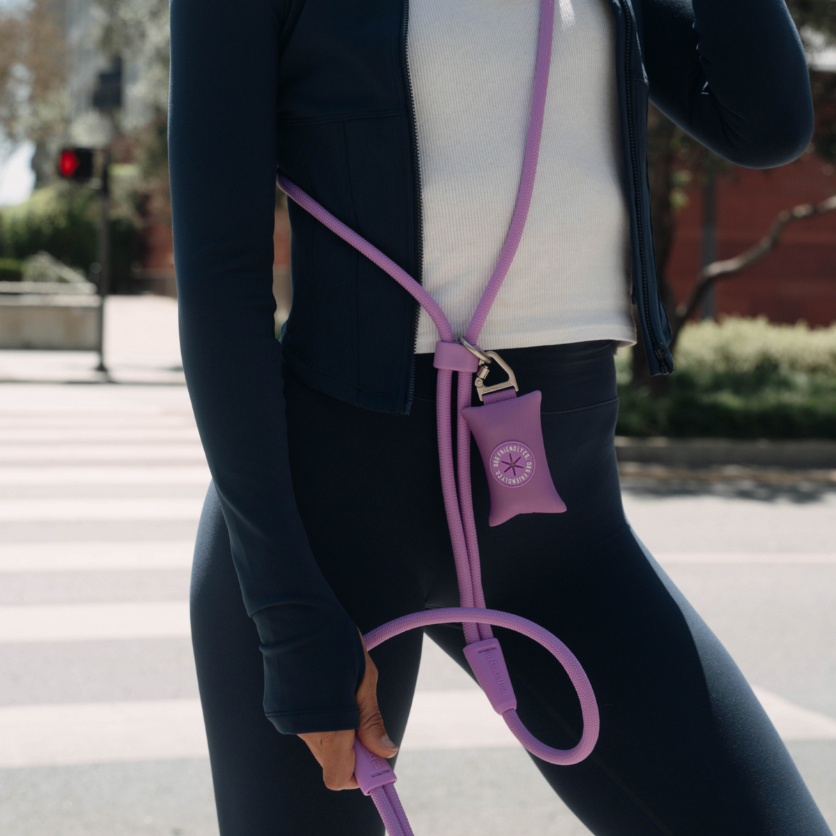 Purple oop bag holder attached to a hands-free dog leash worn around the shoulder